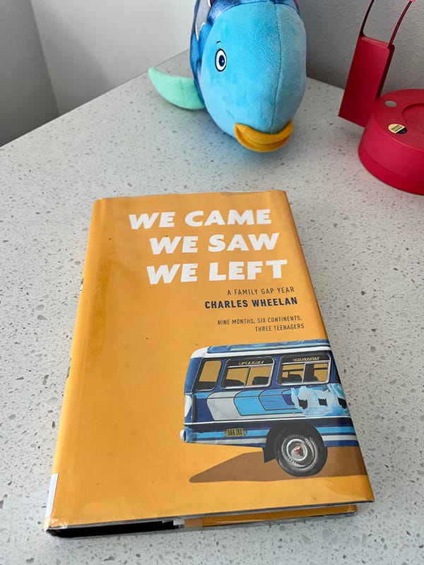 The cloth edition of “We Came, We Saw, We Left” on a desk in front of a plush fish.